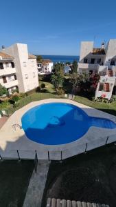 Una gran piscina azul frente a unos edificios. en La Cala playa, en La Cala de Mijas