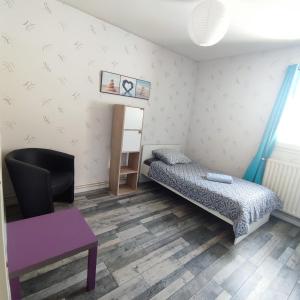 a room with a bed and a chair and a table at LENS, Bel appartement lumineux spacieux en centre ville 3 chambres in Lens