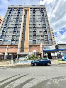 a blue car parked in front of a large building at (604) Studio encantador - Perto da praia in São Luís +35 photos