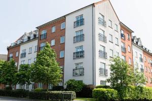 un grand bâtiment blanc avec des arbres devant lui dans l'établissement Greenings Apt Warrington - 2 Bed with FREE off road Parking & Wifi, à Warrington