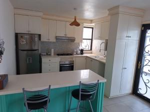 a kitchen with white cabinets and a counter with chairs at Casa de las Dunas in Ciudad Madero