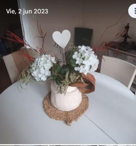 a white vase with flowers on a table at El Marques 28 by emepas in Logroño