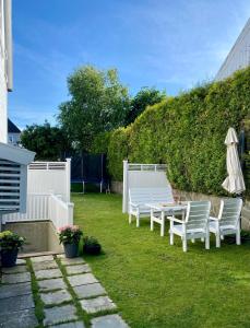 Un patio con sillas blancas y una mesa y una sombrilla. en Down town apartment with outside area in villa, en Kristiansand