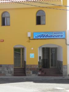 un edificio giallo con due porte e un cartello sopra di Hostal Albacar a Melenara