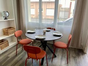 a table and chairs with a table and a window at Les Passe-Pierres in Merlimont