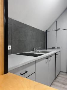 Una cocina con gabinetes blancos y un fregadero. en ROYAL RACiNG SUiTE, en Judenburg