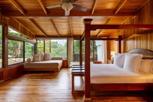 a bedroom with a bed and a couch and windows at Hotel Belmar, a Member of Design Hotels in Monteverde Costa Rica