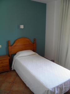 a bedroom with a white bed with a wooden headboard at Hostal Albacar in Melenara