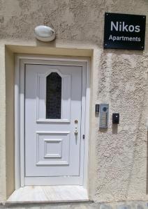 a white door on a building with a sign at Nikos Studio Apartments in Katerini