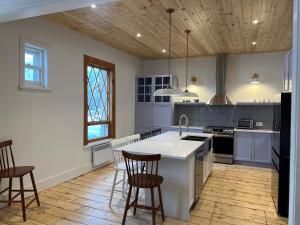 a kitchen with a sink and a counter with stools at Maison du Havre Grand Duplex in La Malbaie