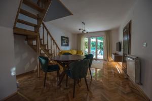 a dining room with a table and chairs and a staircase at Kuća Dragović in Voljevci