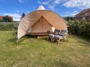 a tent with a chair in the grass at Langø Fjord Glamping NR 2 in Nakskov