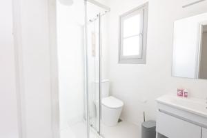 a white bathroom with a toilet and a glass shower at Swell S2 maisonette with private Jacuzzi in Naousa in Naousa +29 photos