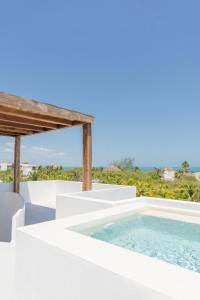 a white villa with a swimming pool and a view of the ocean at COCCOLOBA in Holbox Island