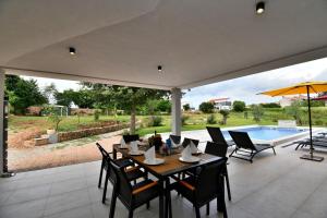 eine Terrasse mit Tisch und Stühlen und einem Pool in der Unterkunft Villa Vala in Marčana