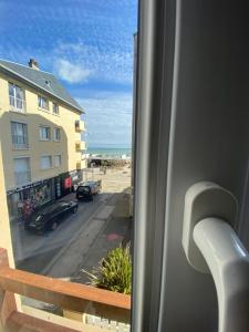 a window with a view of a beach and a car at Appartement duplex Luc sur Mer, en face de la plage in Luc-sur-Mer +20 photos