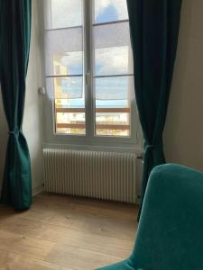 a room with a window with a green chair and a radiator at Appartement duplex Luc sur Mer, en face de la plage in Luc-sur-Mer