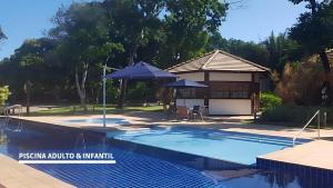 a swimming pool with an umbrella and a house at Apartamento Reserva Time Antube Praia do Forte in Mata de Sao Joao +31 photos