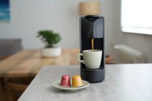 eine Kaffeemaschine mit einer Tasse und Keksen auf einer Theke in der Unterkunft Urban Oasis in Klagenfurt am Wörthersee