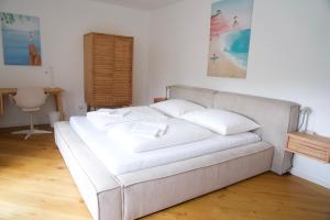 ein weißes Sofa mit Kissen in einem Zimmer in der Unterkunft Urban Oasis in Klagenfurt am Wörthersee + 15 Fotos