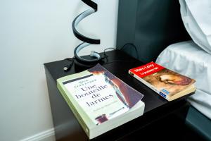 two books sitting on a table next to a bed at Chambre R1 avec salle de bain partagée près de l'hôpital de la Citadelle à Liège in Liège