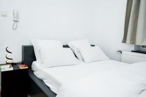 a bedroom with two white beds and a night stand at Chambre R1 avec salle de bain partagée près de l'hôpital de la Citadelle à Liège in Liège