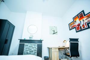 a bedroom with a fireplace and a desk and a chair at Chambre R1 avec salle de bain partagée près de l'hôpital de la Citadelle à Liège in Liège +6 photos