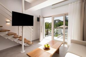 a living room with a tv and a table at Sourinis Luxury Suites in Limenaria