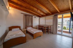 a bedroom with two beds and a table and a window at Villa Hamza Ksamil in Ksamil