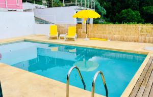 a swimming pool with two chairs and an umbrella at Alto Guest room in Lousã