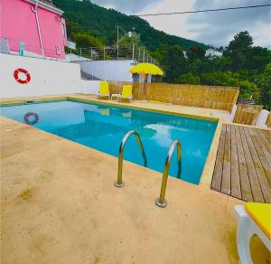 a swimming pool with an umbrella and a wooden deck at Alto Guest room in Lousã