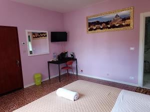 a bedroom with a pink wall with a bed and a desk at Locazione Turistica in Tessera