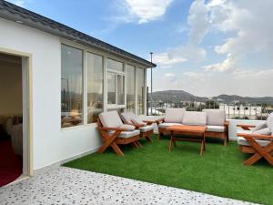 a patio with chairs and a table and grass at فيلا فيو السودة Villa View Al Soudah in Sawdāʼ