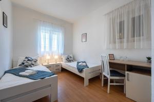 a small room with two beds and a desk and a desk at Bed & Breakfast Blanc in Pučišća