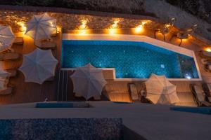 a pool with umbrellas and a table and chairs at Diol Hotel Ksamil in Ksamil