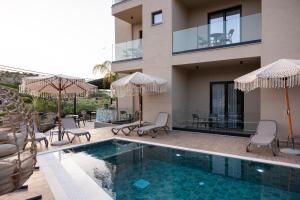 a house with a swimming pool with chairs and umbrellas at Diol Hotel Ksamil in Ksamil