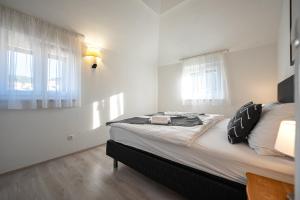 a bedroom with a large bed with two windows at Bed & Breakfast Blanc in Pučišća