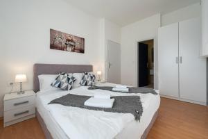 a white bedroom with a large bed with black and white pillows at Bed & Breakfast Blanc in Pučišća