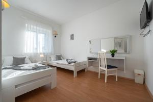 a bedroom with two beds and a desk and a chair at Bed & Breakfast Blanc in Pučišća