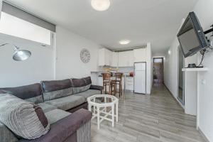 a living room with a couch and a kitchen at Primavera Tranquil Retreat 2-Bedroom Apartment with Balcony, Garden View & Fiber WiFi in Arona