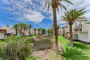 a row of palm trees in front of condos at Primavera Tranquil Retreat 2-Bedroom Apartment with Balcony, Garden View & Fiber WiFi in Arona