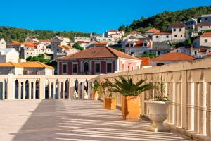 a walkway with potted plants and a city in the background at Bed & Breakfast Blanc in Pučišća