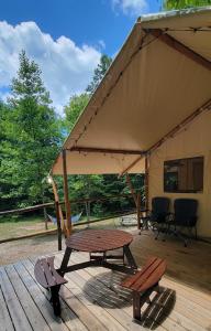 a tent with a picnic table and benches on a wooden deck at Charming enclave Luxury tent in the woods Tent 3 Bambi's playground in Lenoir