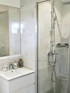 une salle de bain blanche avec une douche et un lavabo dans l'établissement Luxury Apartment - Embassy Gardens, à Accra