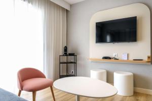 a living room with a white table and a tv at Best Western Plus Ajaccio Amirauté in Ajaccio