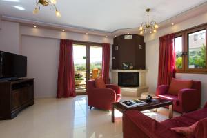 sala de estar con sillas rojas y TV en Villa Sia, en Adelianos Kampos