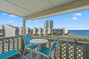 a balcony with chairs and a table and a view of the ocean at Baywatch Unit F10 in Pensacola Beach