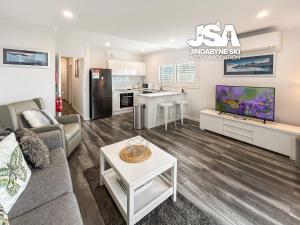 a living room with a couch and a tv at Bundarra One in Jindabyne