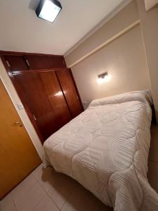 a small bedroom with a bed and a wooden cabinet at Amplio depto a estrenar a metros de plaza principal in San Fernando del Valle de Catamarca