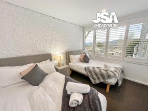 a bedroom with two beds and a window at Bundarra One in Jindabyne